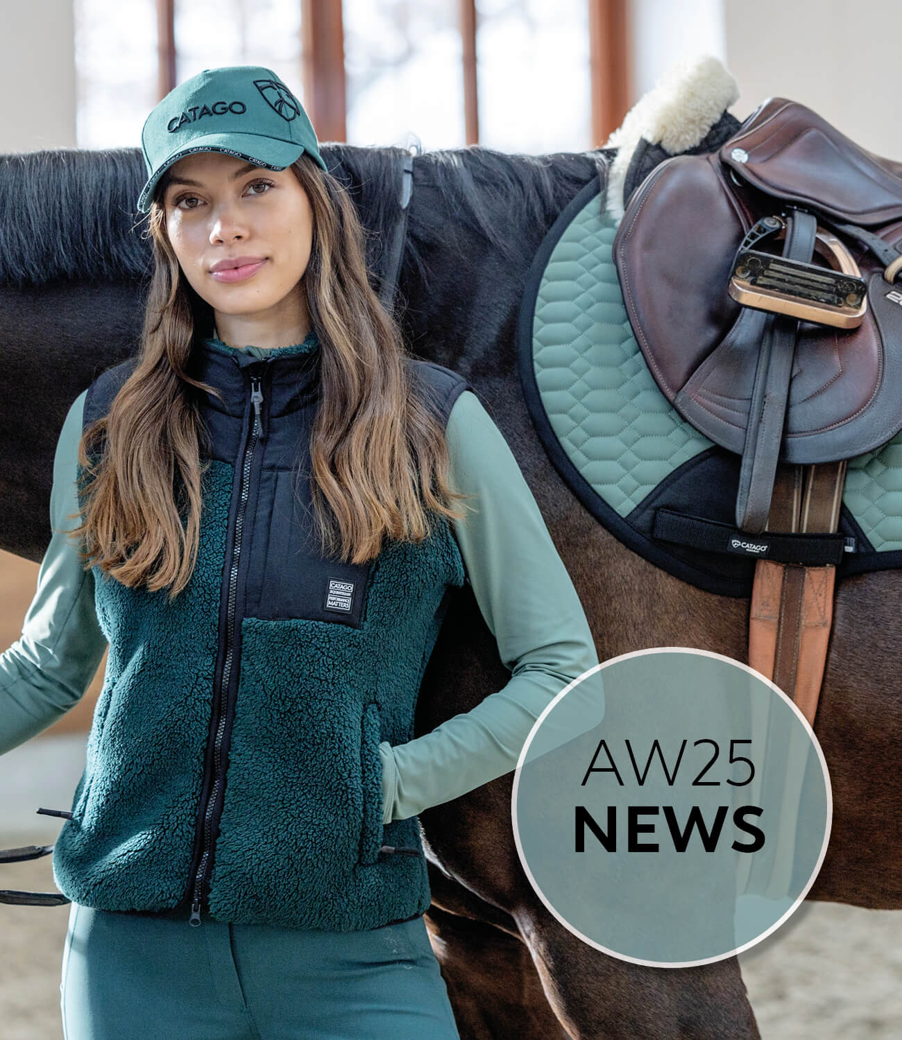 Woman in equestrian gear standing next to a horse with a saddle, wearing a teal cap and jacket.