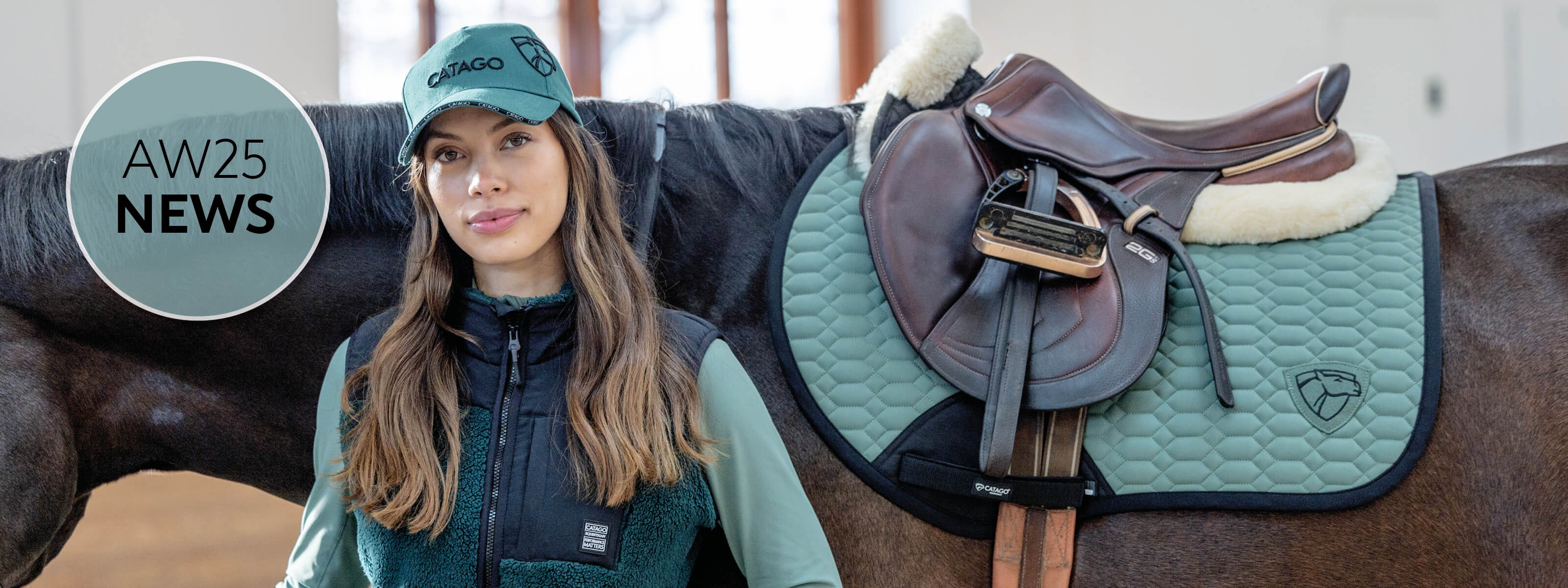 Woman standing next to a horse with a saddle, wearing a teal cap and jacket, with 'AW25 News' text overlay.
