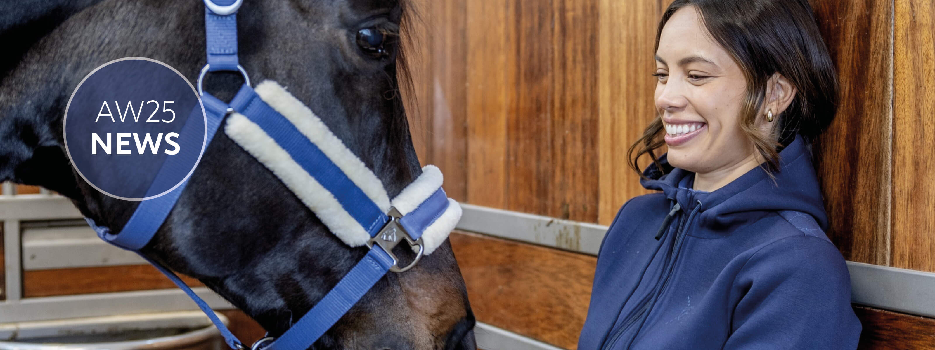 Woman in a blue jacket standing next to a horse with a blue halter, with 'AW25 News' logo.