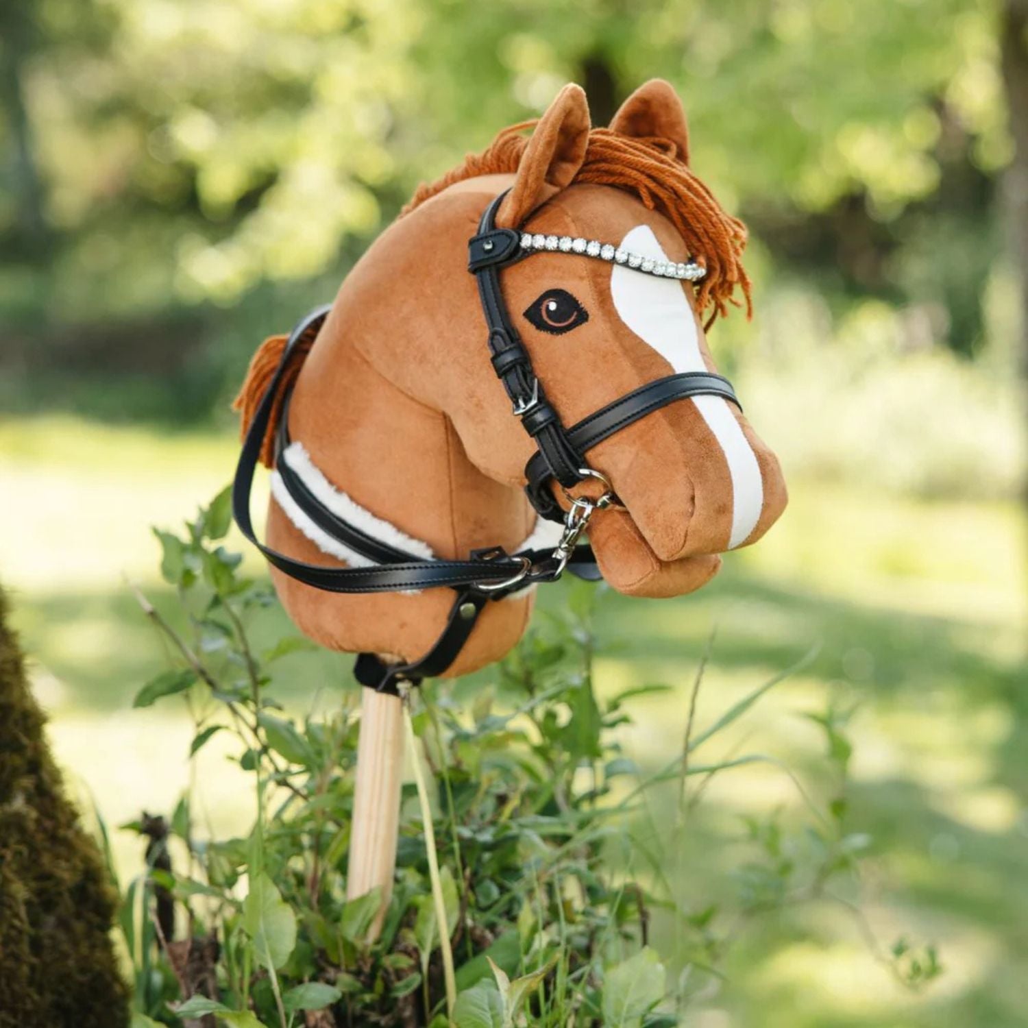 Plush horse toy with bridle in a natural setting