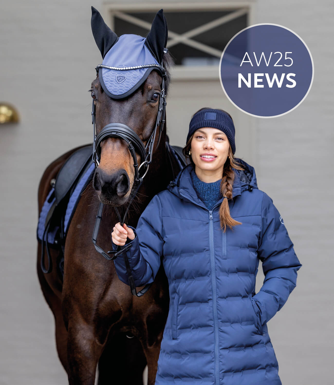 Woman in a blue puffer coat standing next to a horse wearing a blue fly mask, with 'AW25 News' text.